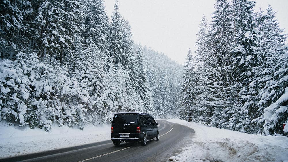 Автомобиль на зимней дороге в Гудаури — зимняя поездка на горнолыжные курорты Грузии